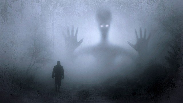 Persona andando hacia un bosque en la niebla, y un alien con los brazos extendidos de fondo esperándola