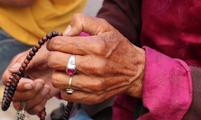 Manos de una anciana contando un rosario